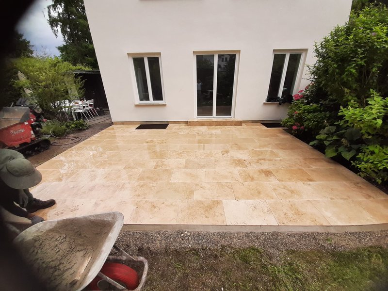 Großzügige Terrasse aus hellen Natursteinplatten im Garten
