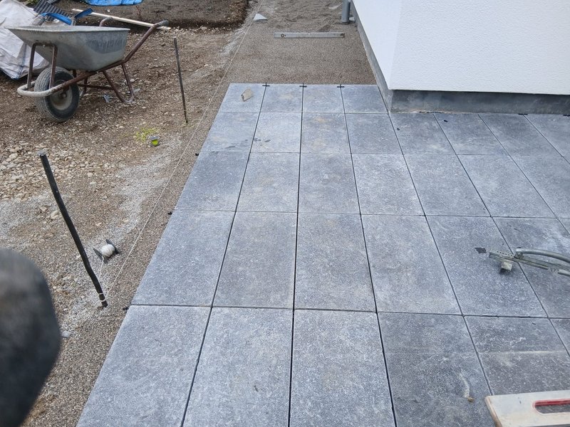 Verlegung grauer Terrassenplatten während der Bauarbeiten
